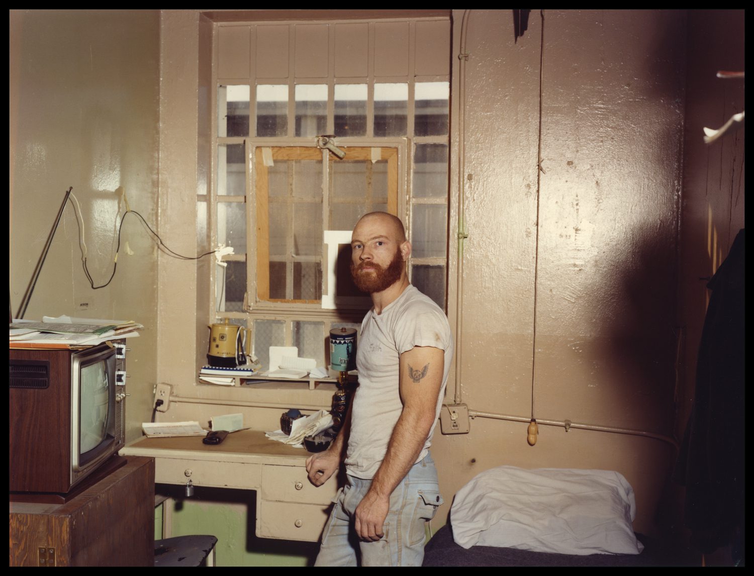 An incarcerated man with a beard stands by a window at MCI-Walpole.