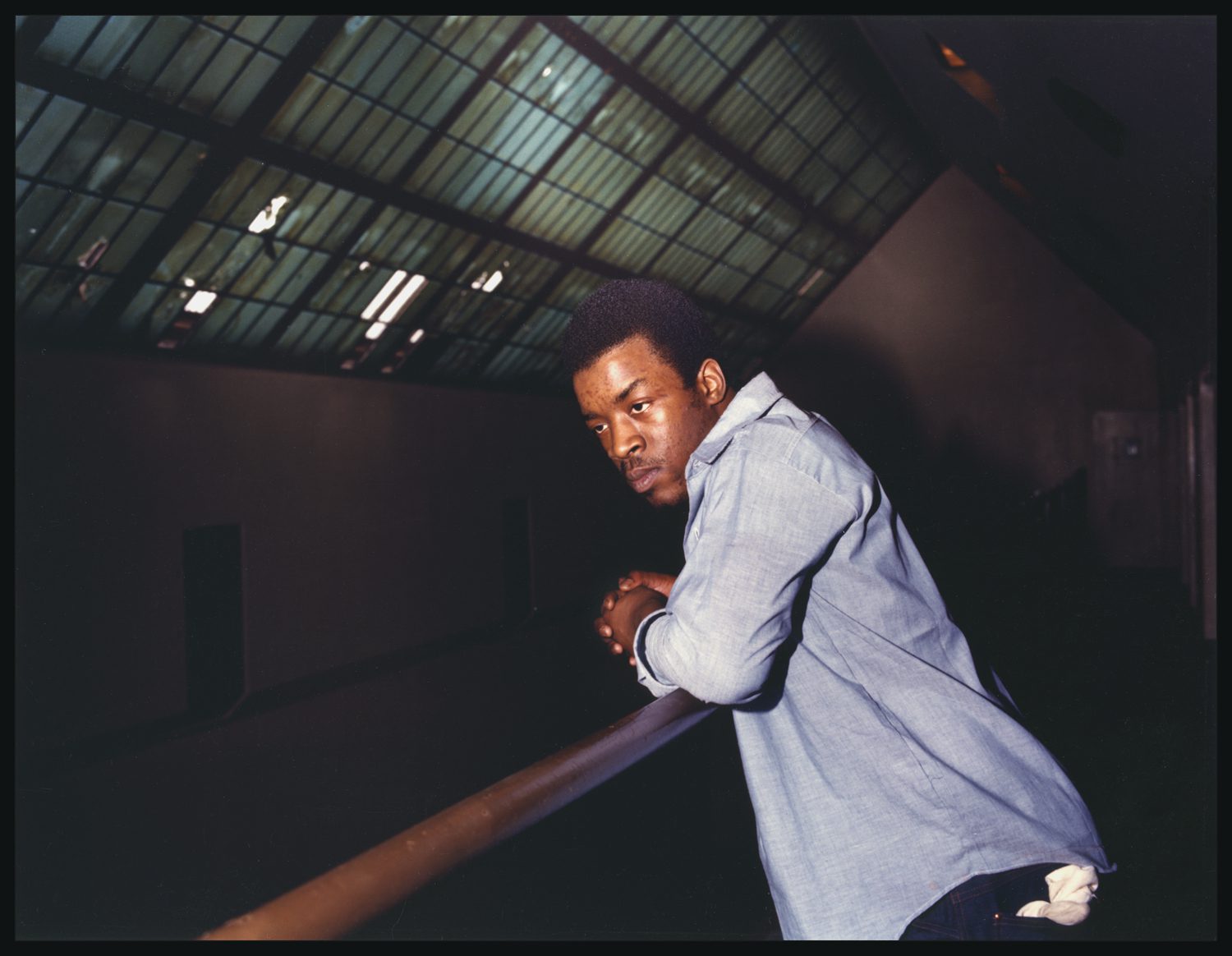 An incarcerated man leans on a balcony rail