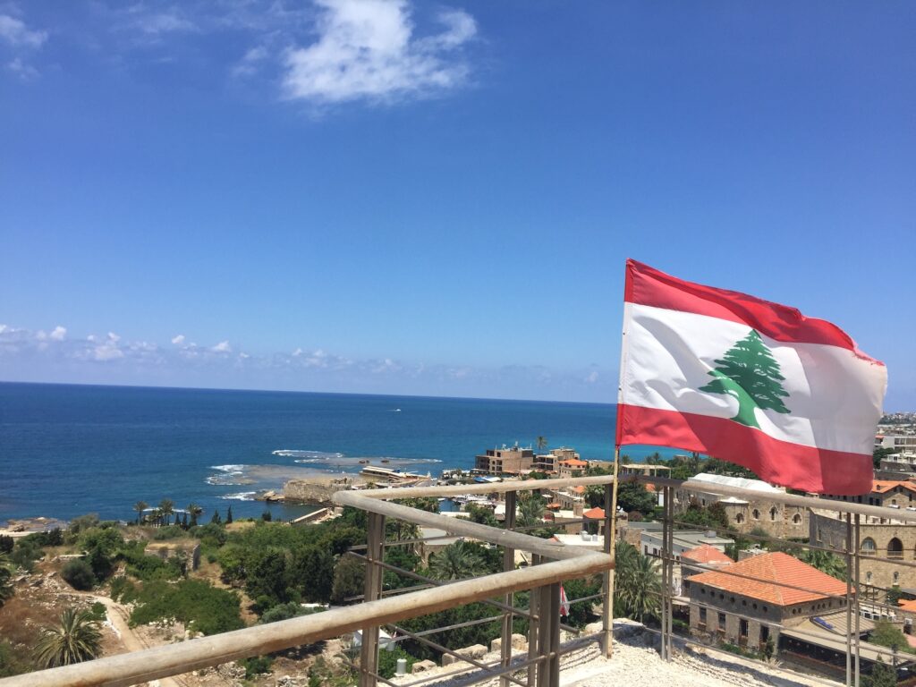 A Lebanese flag waves on a building near the coast.
