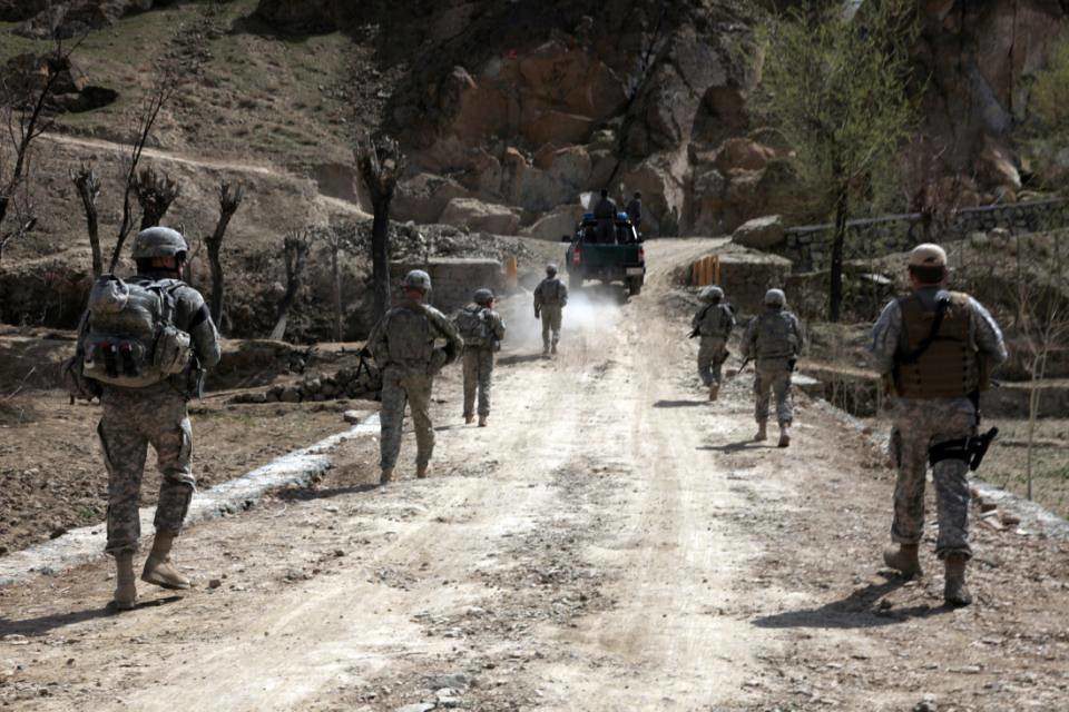 photo of soldiers on a dirt road following a vehicle