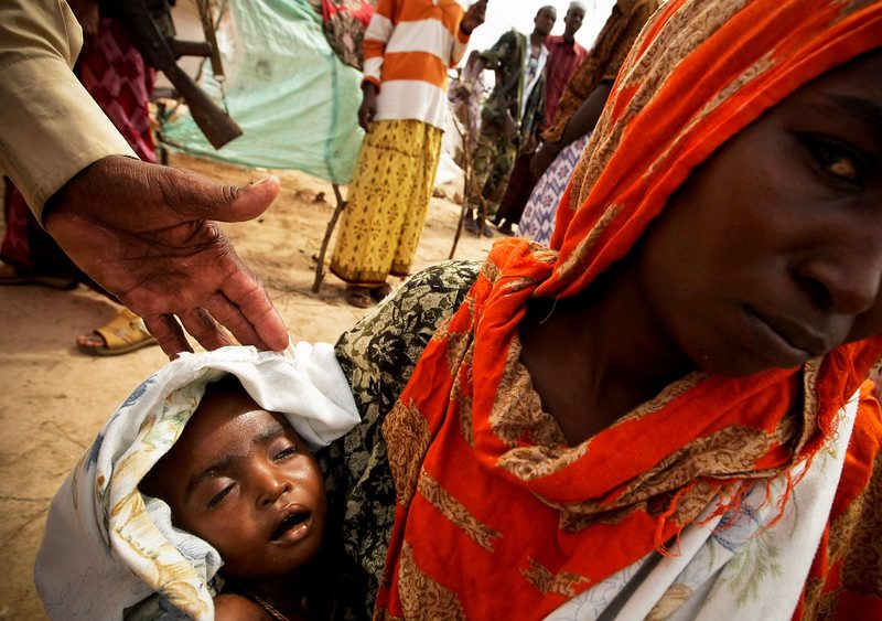 photo of a woman in a red head scarf holding a baby