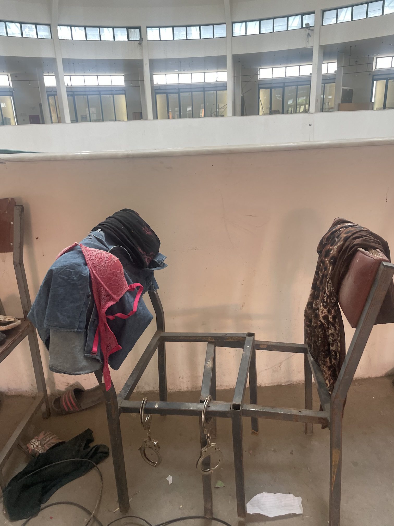 Women’s clothing, including bra and shoes left at the museum, folded over two metal chairs, with handcuffs.