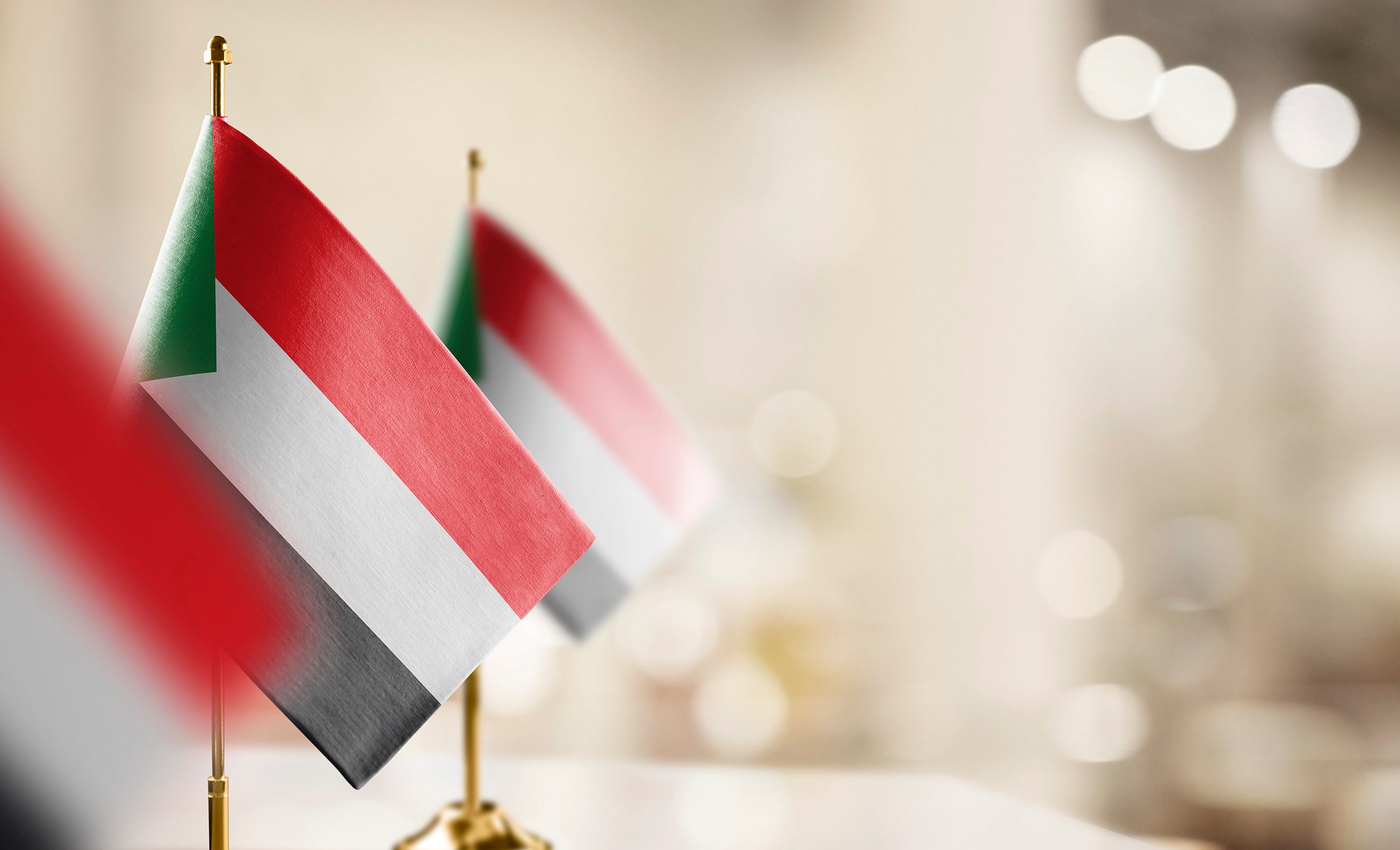 Small flags of the Sudan on an abstract blurry background