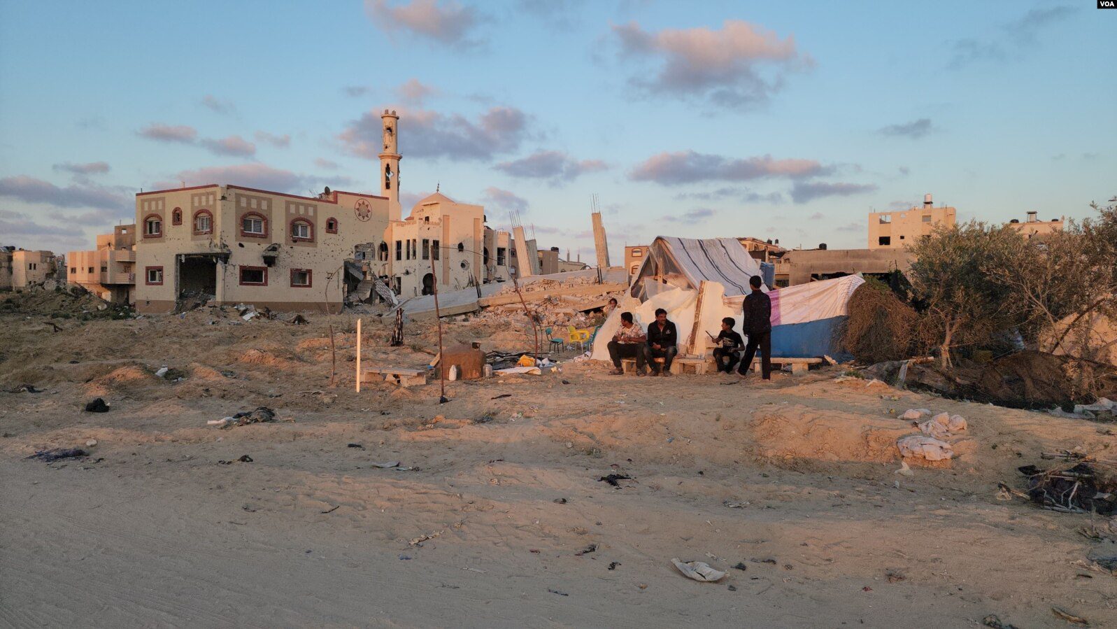 family sheltering in tent outside bombed out city