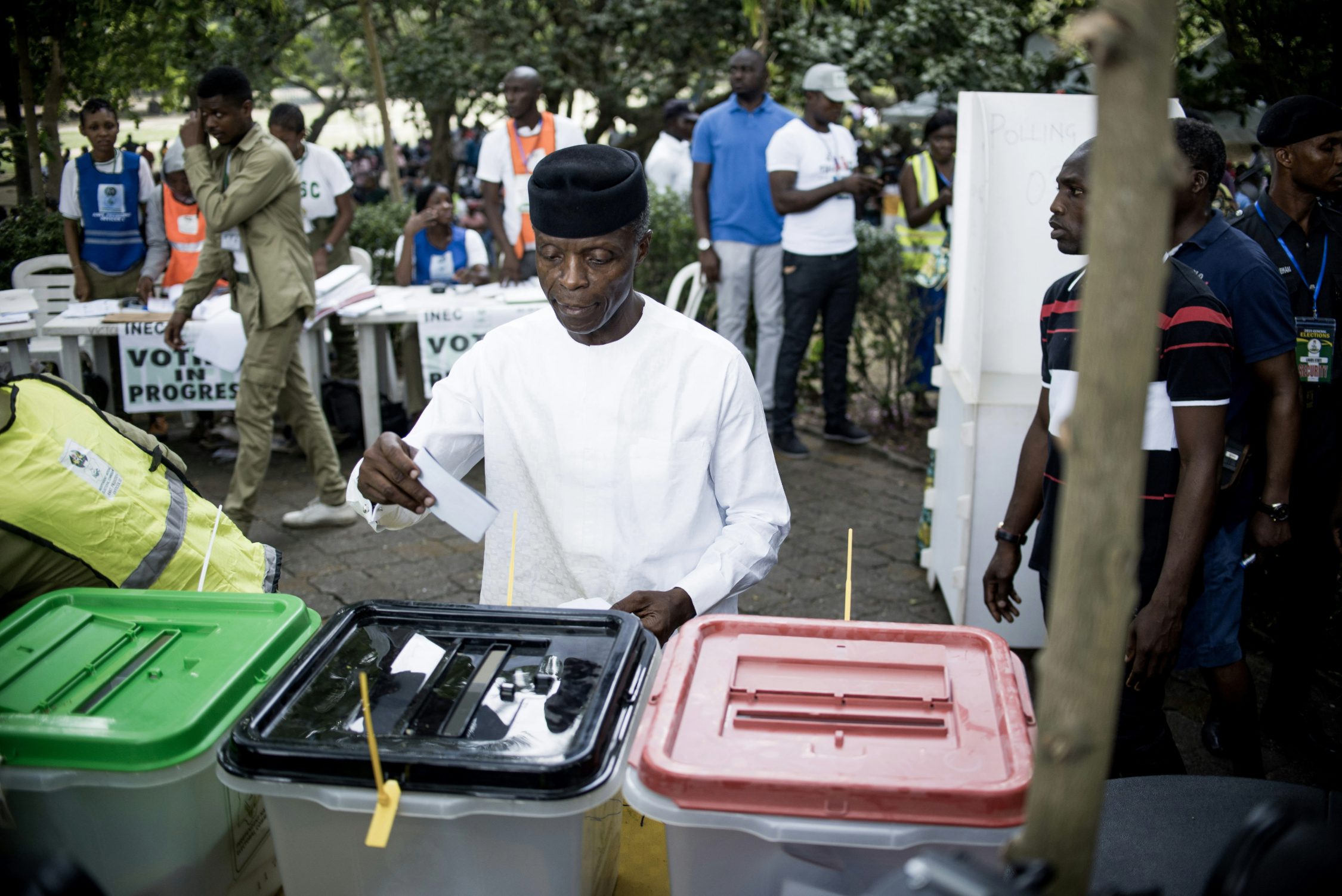photo of a man in white casting vote in box with green, black or red cover.
