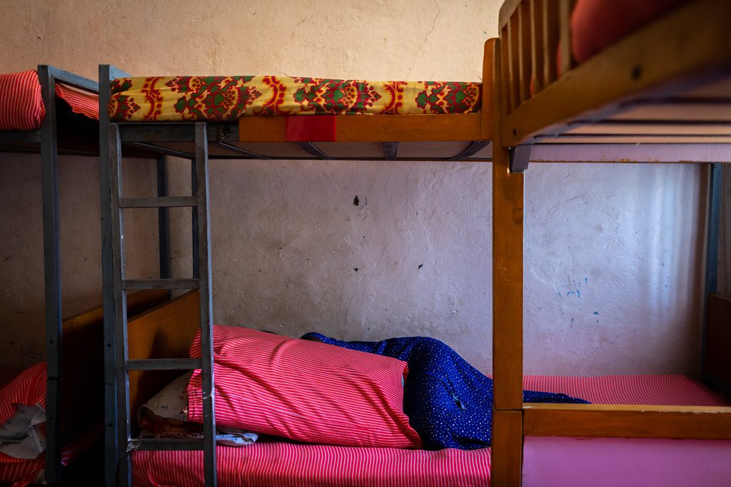 photo of a woman lying on the bottom of a bunk bad, face hidden by pillow