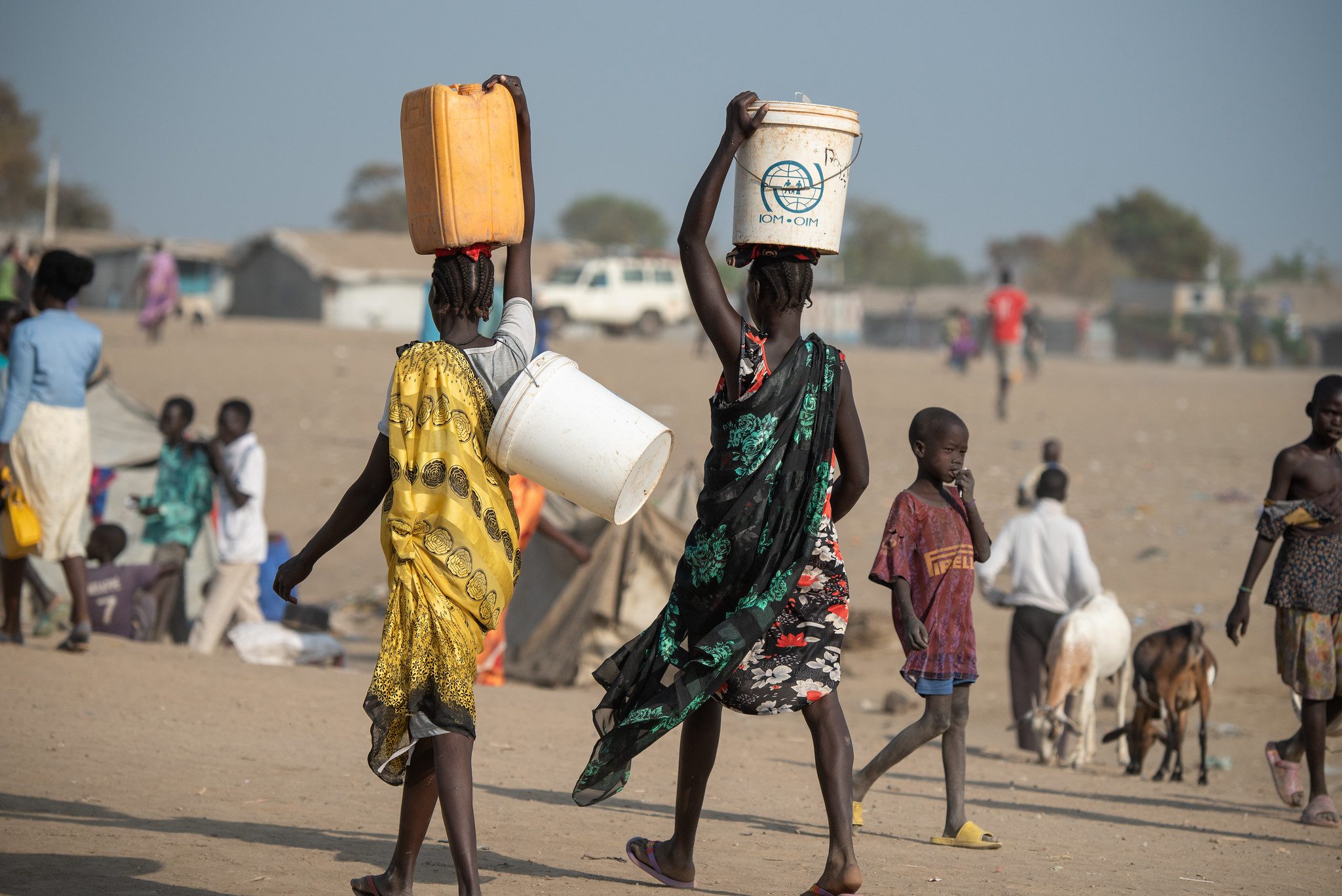 Women in colorful dresses carry water and food on their heads
