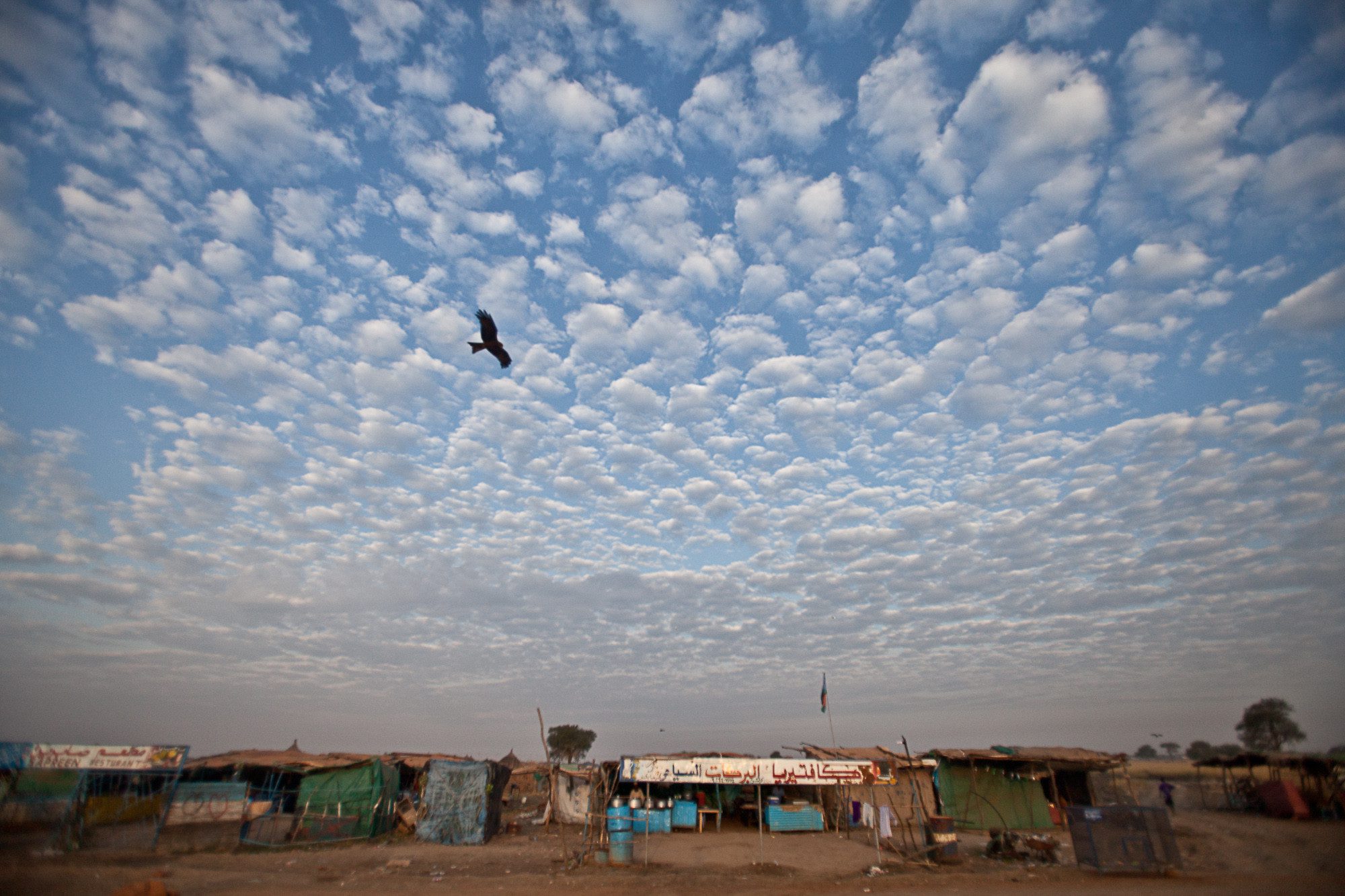 photo of Dusty, windswept Abyei town with blue sky full of clouds